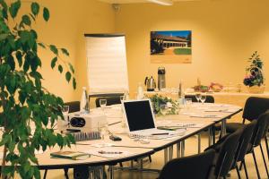 a conference room with a long table with a laptop on it at Logis Hôtel La Petite Chaumière in Gex