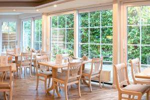 a dining room with tables and chairs and windows at Haus Roseneck mit gratis Zugang zur Jod-Sole-Therme in Bad Bevensen