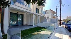 a white house with a glass balcony in front of it at AquaLux Apartment in Kallithea Halkidikis