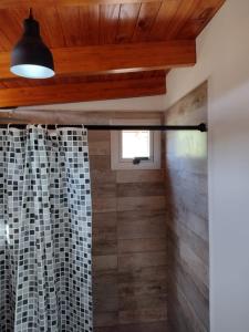 a bathroom with a shower with wooden ceilings and a window at Cabaña La Ilusión in Villa Ciudad Parque