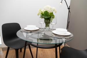 a glass table with two chairs and a vase of flowers at SEKLER Apartments in Cluj-Napoca