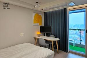 a bedroom with a desk and a bed and a window at Moonlight Sokcho - High-rise, Ocean and City View in Sokcho