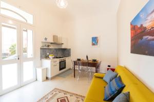 a living room with a yellow couch and a kitchen at Sorelle di Riviera in Syracuse