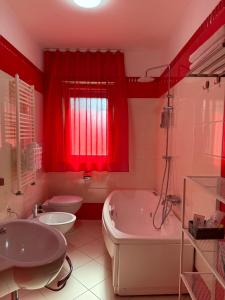 un bagno rosso con vasca e lavandino di Fabiria Guesthouse - B&B a Pagani