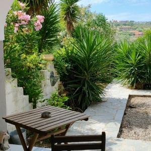 a wooden table and bench in a garden with plants at My corfu house in Agios Stefanos