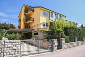 a yellow house with a fence in front of it at Apartmani Kraljevica in Kraljevica
