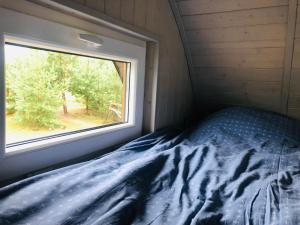 a bed in a small room with a window at Virši Mājīga Māja in Stropi