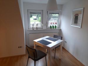 a dining room with a table and chairs and two windows at Casa Tina in Homberg