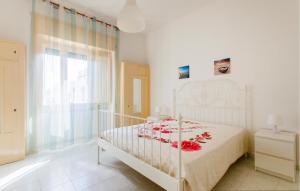 ein Schlafzimmer mit einem weißen Bett mit roten Blumen darauf in der Unterkunft 1 Bedroom Gorgeous Home In Taviano in Taviano