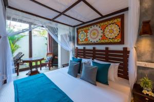 a bedroom with a large bed with blue pillows at Anama by Queens Mount in Tangalle