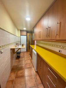 eine große Küche mit Holzschränken und einer gelben Theke in der Unterkunft Beach Apartment Tropical Golf in Motril