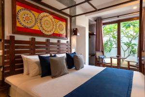 a bedroom with a large bed with blue and white pillows at Anama by Queens Mount in Tangalle