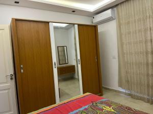 a bedroom with a wooden door and a mirror at Stylish 2-Bedroom Apartment in Celia Compound, New Administrative Capital in Madīnat al Amal