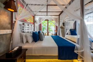 a bedroom with a large bed with blue pillows at Anama by Queens Mount in Tangalle