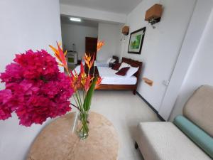 a living room with a vase of flowers on a table at Jasmin Apartments flic en flac in Flic-en-Flac