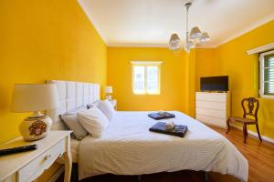 a bedroom with a white bed with yellow walls at Beach & Nature Villa with Amazing Pool by TimeCooler in Setúbal