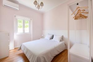 a white bedroom with a bed and a window at Beach & Nature Villa with Amazing Pool by TimeCooler in Setúbal +37 photos