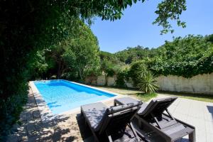 a swimming pool with two chairs and a table at Beach & Nature Villa with Amazing Pool by TimeCooler in Setúbal