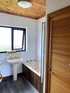 a bathroom with a sink and a bath tub next to a window at Eileen's Cottage in Castlerock