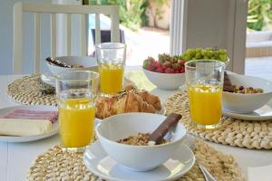 a table with a breakfast of orange juice and food at Beach & Nature Villa with Amazing Pool by TimeCooler in Setúbal