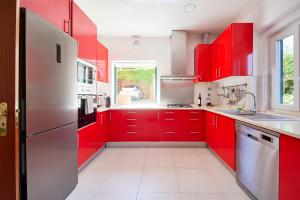 a red kitchen with red cabinets and a window at Beach & Nature Villa with Amazing Pool by TimeCooler in Setúbal