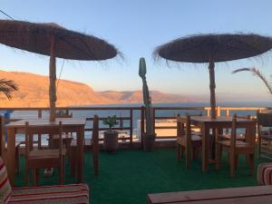 un patio con tavoli e ombrelloni e vista sull'oceano di Padova Surf House a Imsouane