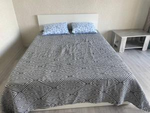 a bed with a black and white comforter in a room at Шатман in Chyrpykty