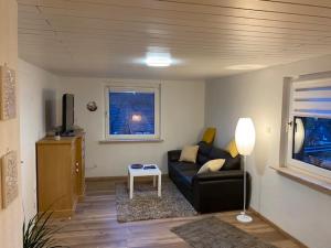Una sala de estar con un sofá negro y una ventana. en Niederfischbach Ferienwohnung, en Niederfischbach
