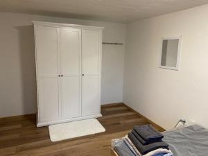 1 dormitorio con armario blanco y suelo de madera en Niederfischbach Ferienwohnung, en Niederfischbach