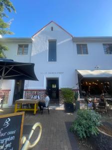 a white building with people sitting at tables in front of it at Boho Chic Studio Stellenbosch in Stellenbosch