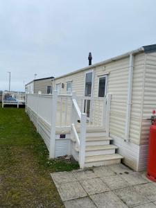 a white mobile home with stairs next to it at Thistle 83 in Porthcawl +6 photos