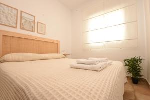 a bedroom with a white bed with towels on it at BITA Home in Barbate