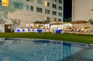 a pool with chairs and tables and a building at Royal Plaza Hotel in Tiberias