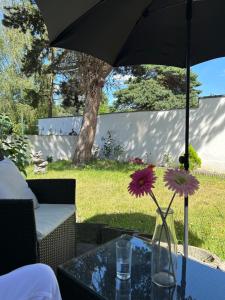 a vase with flowers on a table under an umbrella at Apartment im Düsseldorfer Norden in Düsseldorf +16 photos