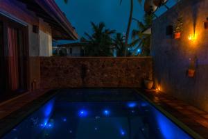 a pool with blue lights in a backyard at night at Anama by Queens Mount in Tangalle