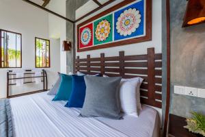 a bedroom with a bed with blue and white pillows at Anama by Queens Mount in Tangalle