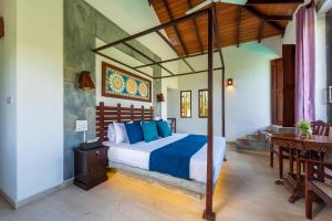 a bedroom with a bed with blue pillows at Anama by Queens Mount in Tangalle