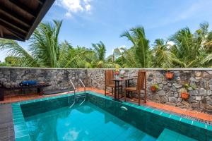 a pool with a table and chairs next to a stone wall at Anama by Queens Mount in Tangalle