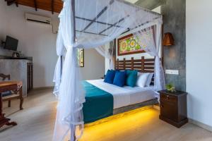 a bedroom with a canopy bed with blue pillows at Anama by Queens Mount in Tangalle