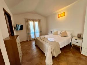 a bedroom with a large white bed and a television at Villa Sunrise in Budoni