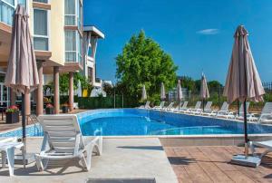 a pool with chairs and umbrellas next to a building at Студия 310 и 312 на първа линия in Chernomorets
