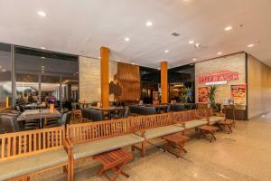 a restaurant with wooden benches and tables and chairs at Suíte Moderna com acesso ao Shopping in Brasilia