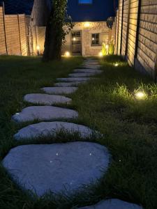 a walkway in the yard at night with lights at La maison d Aurore loft et spa privatif in Couvin