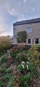 une maison en briques avec un jardin devant dans l'établissement Balkcote ground floor cosy apartment, à Romaldkirk
