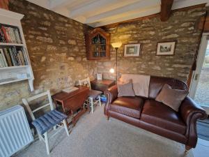 un salon avec un canapé en cuir et une table dans l'établissement Balkcote ground floor cosy apartment, à Romaldkirk