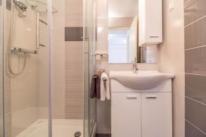 a white bathroom with a sink and a shower at Apartment MiMa in Medulin