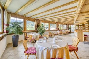 a dining room with tables and chairs and windows at Das Bergland - Vital & Activity in San Leonardo in Passiria