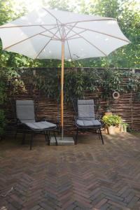 Dos sillas bajo una sombrilla en un patio. en natural green loft, en Bergen