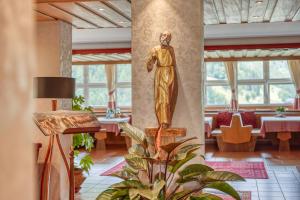a statue of a woman in a room with tables at Das Bergland - Vital & Activity in San Leonardo in Passiria