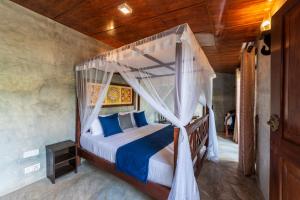 a bedroom with a canopy bed with blue pillows at Anama by Queens Mount in Tangalle